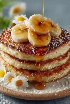 Stack of fluffy banana pancakes drizzled with syrup and garnished with sliced bananas